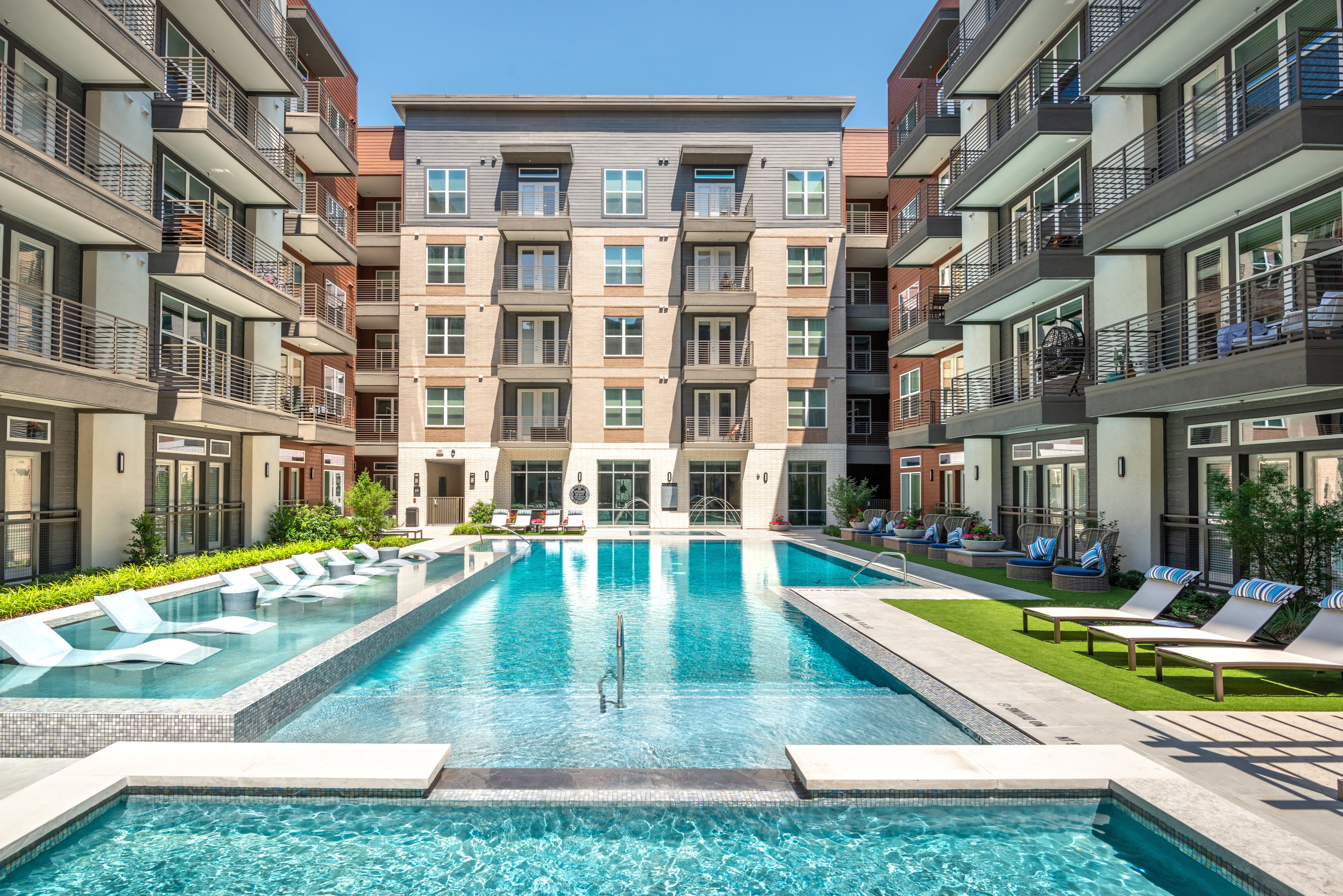 swimming pool with surrounding building and lounge chairs